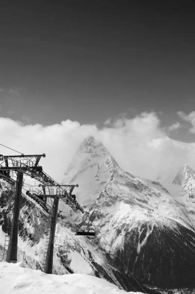 スキー場でのチェアリフトの黒と白の景色と太陽の光の雲の中の山 冬のドムベイ地方のコーカサス山脈 — ストック写真