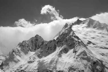 Karlı buzullardaki kayak yamaçlarından ve bulutlardaki dağ zirvelerinden siyah beyaz manzara. Kafkasya Dağları kış akşamı, Dombay bölgesi. Peak Ine.