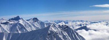 Bulutlardaki karlı dağlar manzarası ve güzel bir kış gününde mavi gökyüzü. Kafkasya Dağları, Gürcistan, Gudauri bölgesi.