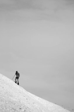 Kayakçı, karlı, serbest yamaçta ve bulutlu gökyüzünde tepeden önce gelir. Kışın Kafkasya Dağları, Gürcistan, Gudauri bölgesi. Siyah ve beyaz tonlu manzara.