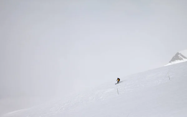 Skifahrer Bergab Auf Schneebedeckter Piste Und Berge Nebel Grauen Wintertag — Stockfoto