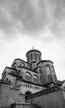 Tsminda Sameba Katedrali ya da Kutsal Üçlü Katedrali ve bulutlu gri gökyüzü. Gürcistan 'ın başkenti Tiflis' teki Gürcistan Ortodoks Kilisesi 'nin ana katedrali. Siyah ve beyaz geniş açı. Yüksek karşıtlık