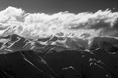 Bulutlar ve paraglider siluetiyle akşam güneşi dağı. Kafkas Dağları. Georgia, Gudauri kayak merkezi. Siyah ve beyaz tonlu manzara.