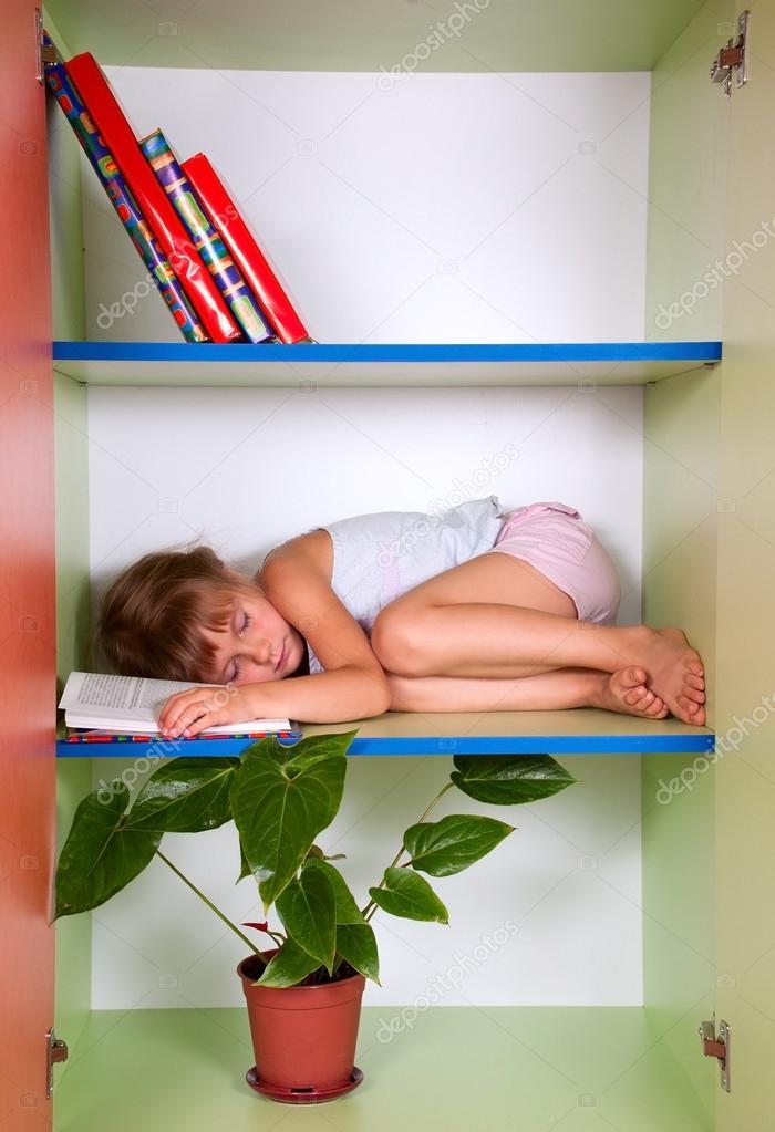 tired kid sleeping on the shelf with a book instead of a pillow