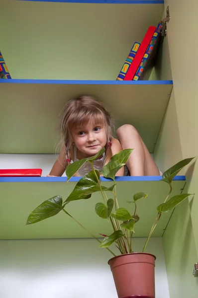 Playful little girl hiding on the shelf — Stock Photo, Image