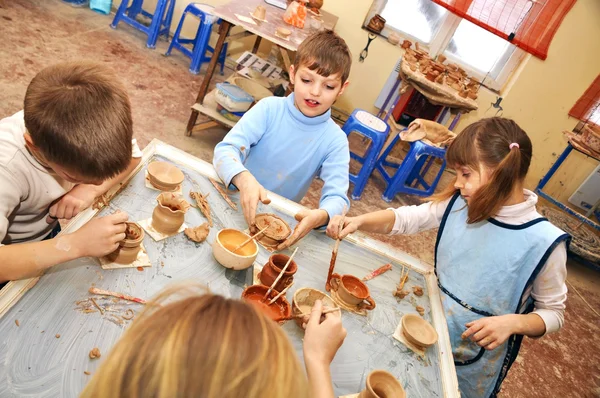 Groupe d'enfants façonnant l'argile en atelier de poterie — Photo