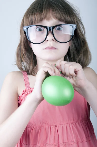 Menina engraçada com óculos de sol de rebanho soprando um balão — Fotografia de Stock