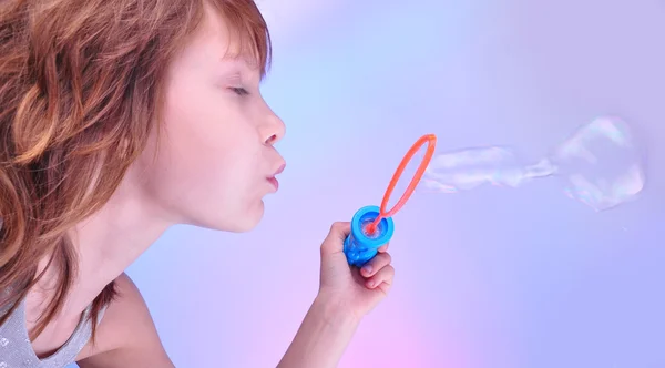 Flicka blåser såpbubblor mot ljus bakgrund — Stockfoto