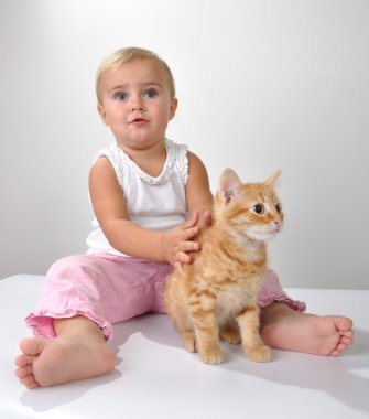 yürümeye başlayan çocuk bir kedi ile oynuyor