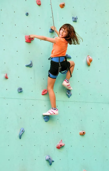 Smiling child climbing up the wall — Stock Photo, Image
