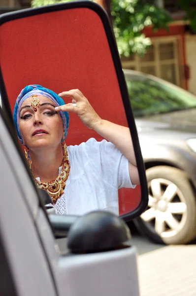 Žena s indickými jewlery pohledu na auto zrcadlo na ulici — Stock fotografie