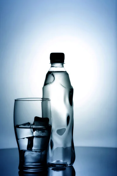 Ποτήρι κρύο νερό με πάγο και πλαστικό μπουκάλι — Φωτογραφία Αρχείου