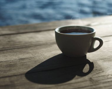 Nehir kıyısında bir sabah. Masanın üzerinde bir fincan lezzetli aromatik kahve.