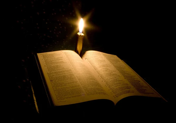 A bible open on a table with candle — Stock Photo, Image