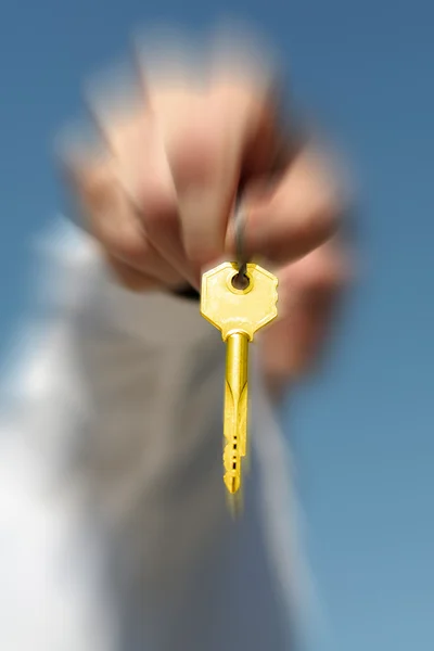 Mão segura uma chave de ouro — Fotografia de Stock