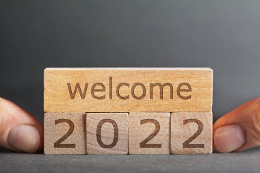 Gri arka planda parmakları olan bloklara işlenmiş 2022 yazısına hoş geldiniz.