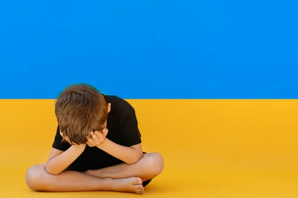 坐在乌克兰国旗上的男孩 — 图库照片
