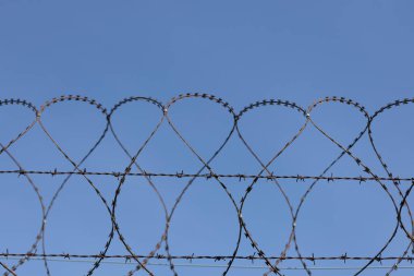 Mavi gökyüzüne karşı dikenli tel