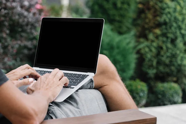 a man works in nature, sitting in a chair with a laptop