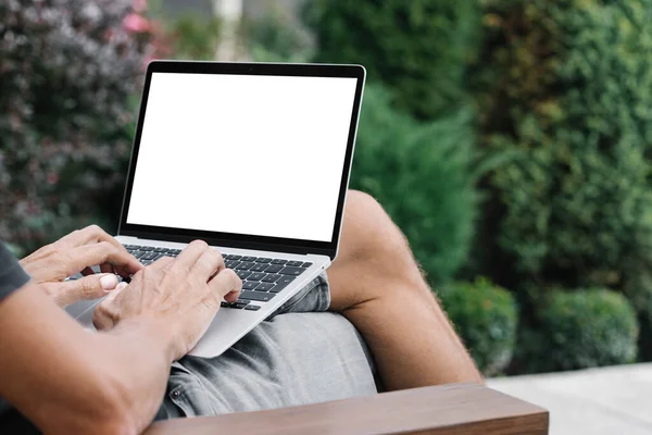 a man works in nature, sitting in a chair with a laptop