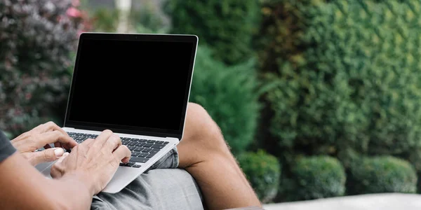 a man works in nature, sitting in a chair with a laptop