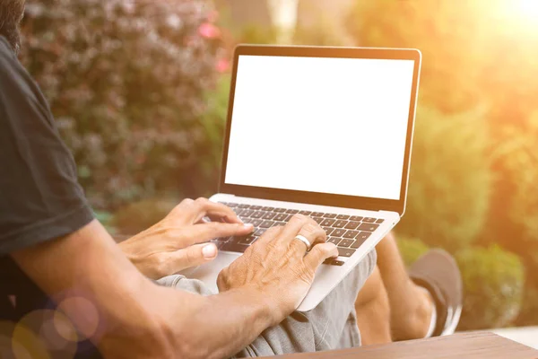a man works in nature, sitting in a chair with a laptop