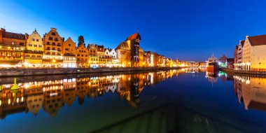 Scenic night panorama of the Old Town pier architecture of Gdansk, Poland at the Motlawa River harbor embankment with medieval port crane and historical ships