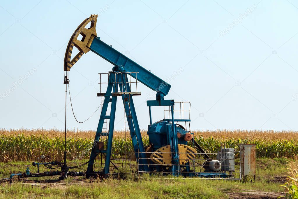 Landscape with the oil pumpjack and crop field