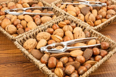 Kahverengi arka planda üç konteynırda fındık kıran çeşitli fındıklar.