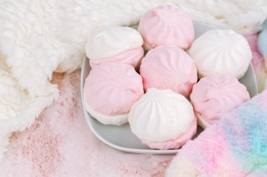 Beyaz tabakta Rus tatlı zefiri ya da zephyr, pembe arka planda renkli ve beyaz kürk eşarplar. Marshmallow yakın çekim resmi.