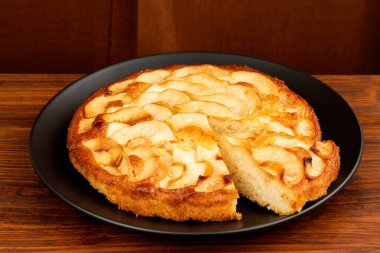 Kahverengi tahtada siyah tabakta elmalı turta. Kırmızı arka plan. Yan yatay görünüm.