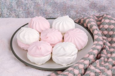 Rus tatlı zefiri ya da pembe kürk arka planında gri tabakta zephyr. Şekerleme ve örgü eşarp yakın çekim resmi. 