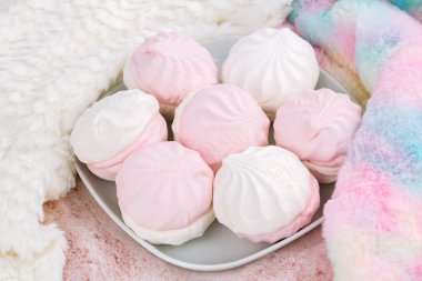 Beyaz tabakta Rus tatlı zefiri ya da zephyr, pembe arka planda renkli ve beyaz kürk eşarplar. Marshmallow yakın çekim resmi.