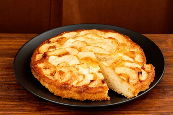 Kahverengi tahtada siyah tabakta elmalı turta. Kırmızı arka plan. Yan yatay görünüm.