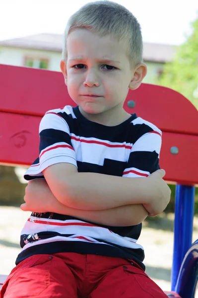 Rapazinho sério sentado no parque infantil — Fotografia de Stock