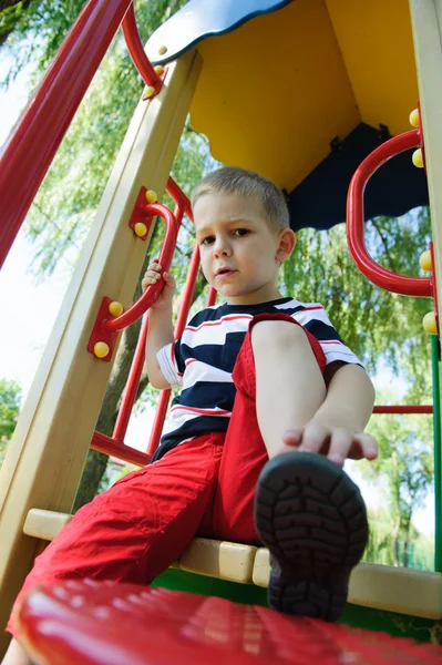 Rapazinho sério sentado no parque infantil — Fotografia de Stock