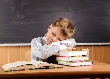 Uyuyan çocuk masasında kitaplar