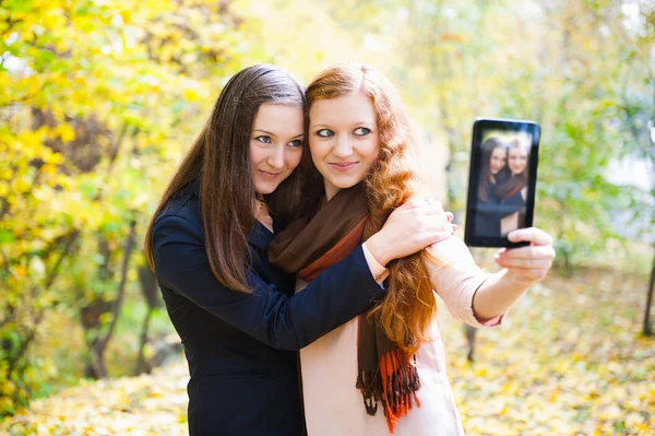 Two girls taking self portrait in autumn park — Stock Photo, Image