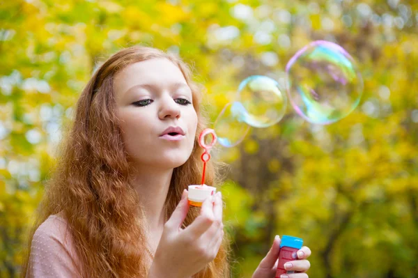 Молодая рыжая девушка пускает пузыри — стоковое фото