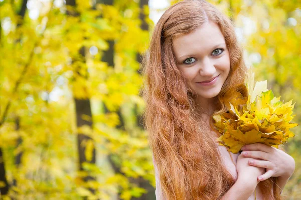 Рыжая девушка с желтыми осенними листьями — стоковое фото