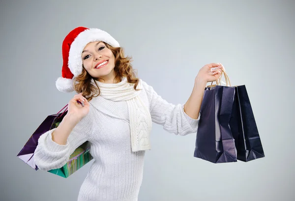 Mooi meisje in Kerstman hoed met shopping tassen — Stockfoto