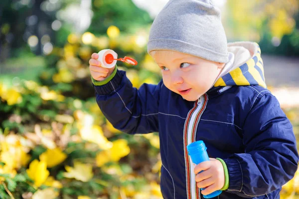 Lille pojken blåser såpbubblor i höst park — Stockfoto