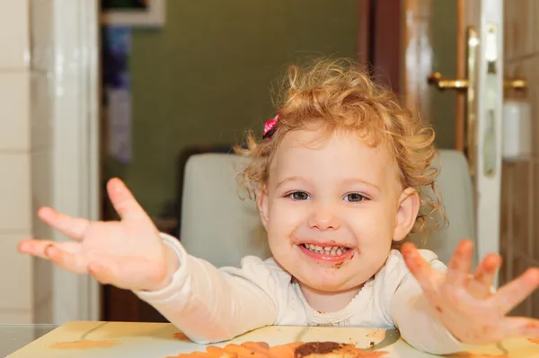 Menina com rosto sujo comer biscoito — Fotografia de Stock