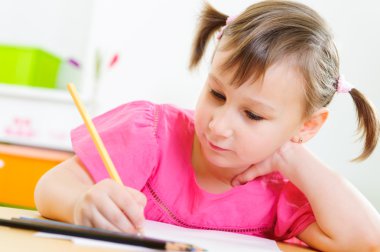 Güzel küçük kız evde ders çalışıyor.