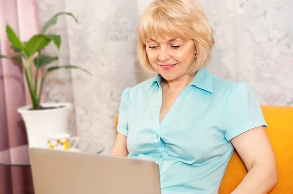 Gelukkig volwassen vrouw met laptop thuis — Stockfoto