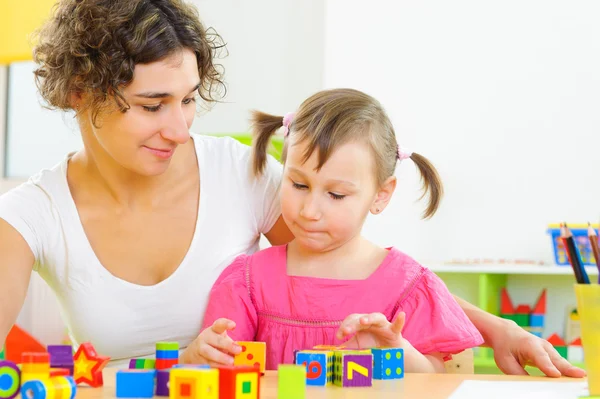 Joven madre e hija pequeña jugando con bloques de juguetes — Foto de Stock