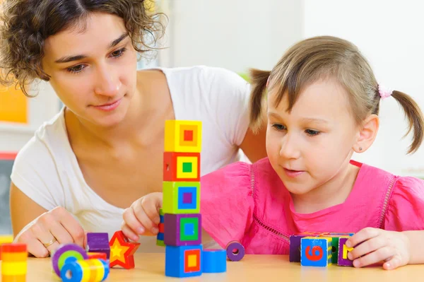 Joven madre e hija pequeña jugando con bloques de juguetes — Foto de Stock