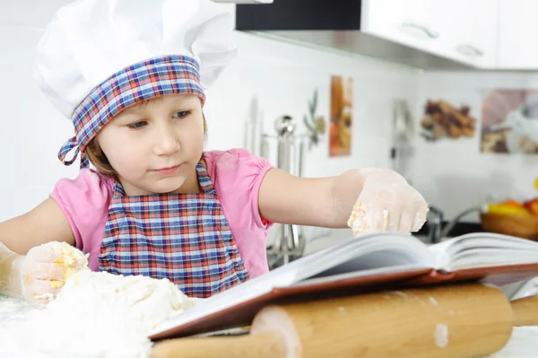 Niña preparando galletas con libro de cocina — Foto de Stock