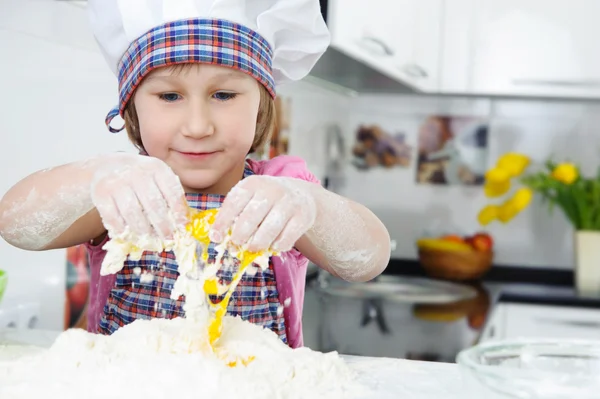 Söt liten flicka i förkläde matlagning cookies — Stockfoto