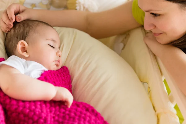 Jonge moeder zitten in de buurt van slapende baby — Stockfoto